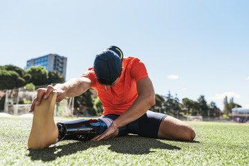 Disabled man athlete stretching with leg prosthesis.