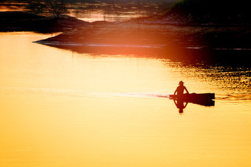 The man sailing boat in the river at sunset after fishing time,silhouette abstract background.