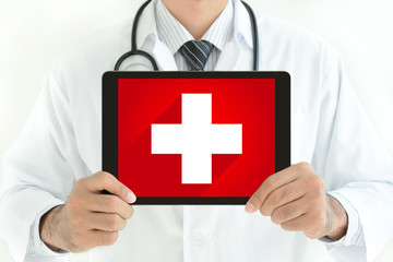 Doctor holding tablet pc with first aid sign on screen