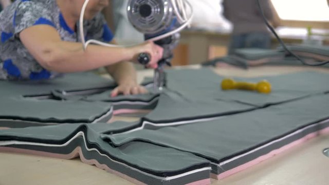Tailors slowly cut out pattern shapes on fabric. 