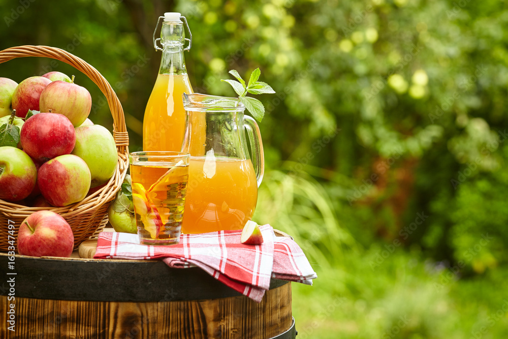 Wall mural Basket of apples on background orchard standing on a barrel. Apple juice and apple preserves.