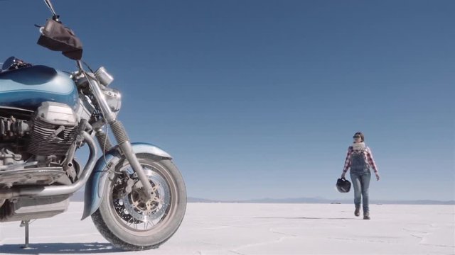Female motorcyclist walks near custom bike