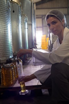 Portrait of female technician examining olive oil