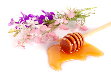 Honey stick with flowing honey and wildflowers isolated on white background