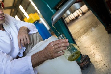 Technician examining olive oil produced from machine