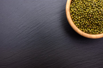 mung bean in a wooden cup on a black stone board background, space for text, beans