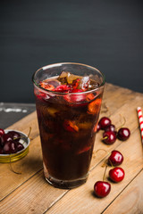 Refreshing cold cherry cola on the wooden background