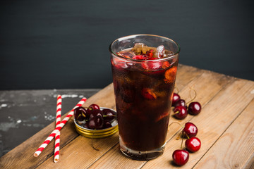 Refreshing cold cherry cola on the wooden background