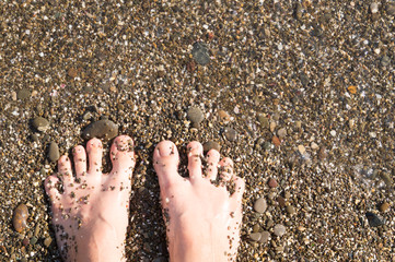 Vacation concept. Sandy woman feet on the beach and sand