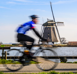 Obraz premium Purposely blurred cyclist and a windmill in the Netherlands