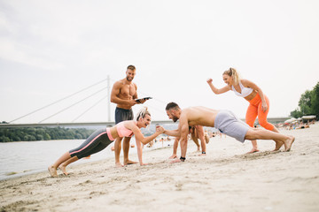 Fototapeta na wymiar Group young attractive people having fun on beach and doing some fitness workout. 