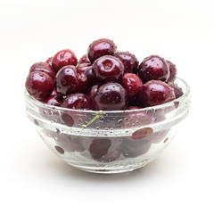 Glass vase with fresh wet cherries isolated on white background