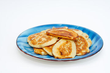 Ruddy freshly cooked pancakes lie on a blue plate on a white background.