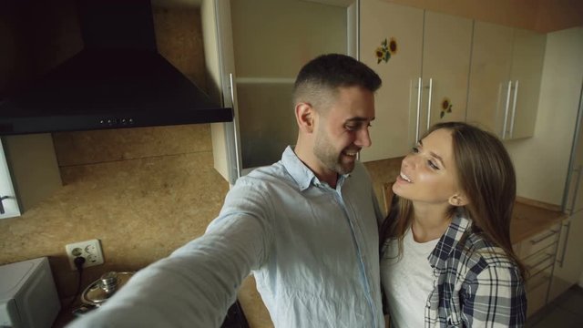 Young happy couple having online video chat in the kitchen at home