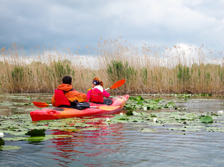 Family kayaking on the Danube river with stormy sky with clouds. Active man and woman having fun...