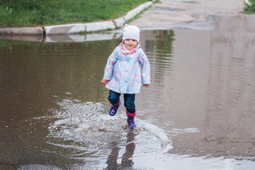 Child jumping in the muddy puddle