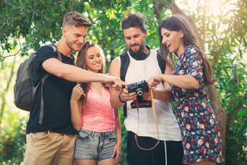 Group of friends or couples having fun with photo camera in summer park