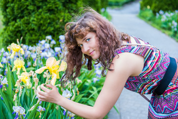 Young woman holding and smelling yellow iris flowers in park during summer outside