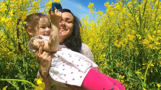 Happy family mother and child daughter have fun on yellow flowers