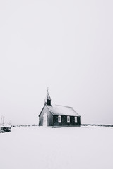 Piękny minimalistyczny widok Budir czarny kościół na półwyspie Snaefellsnes podczas ostrej śnieżycy - 163359863