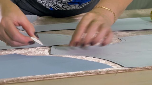 A tailor uses white piece of chalk to transfer patterns