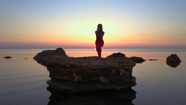 Young girl do Yoga garudasana eagle pose sea reef dawn drone footage aerial