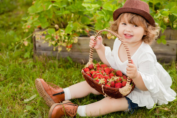 Adorable little girl with the basket full of stawberry