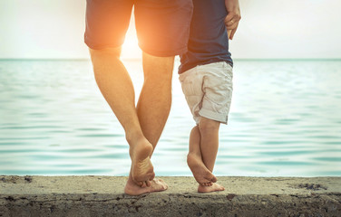 Father and son stay on the sea beach under sunlight at summer ti