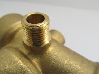 Gold pipe fittings thread of a mechanical element close-up on a white background