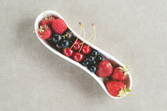 Assorted fresh garden berries on a grey background. Space for text.