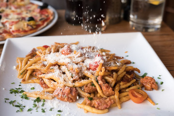 Pasta with Tomato sauce, Sprinkling Cheese. On plate in the restaurant.