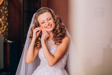 Fototapeta premium Portrait of beautiful bride model with perfect makeup and hair style in light room in a morning