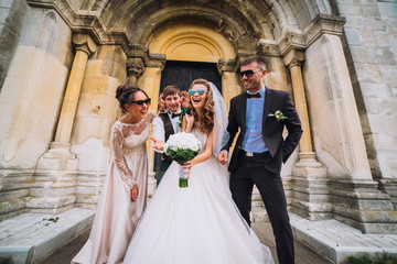 Full length portrait of newlywed couple dancing and having fun with bridesmaids and groomsmen in...