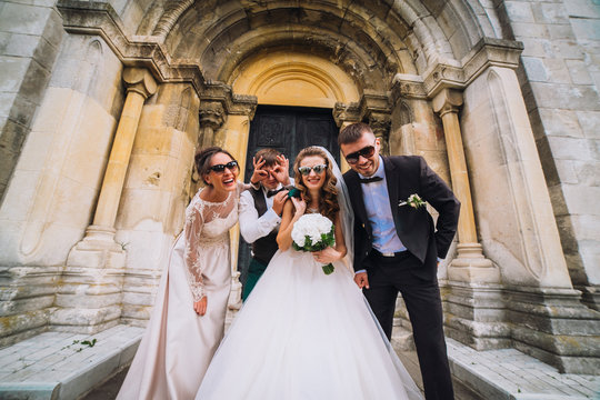 Full length portrait of newlywed couple dancing and having fun with bridesmaids and groomsmen in the city. Boys and girls in glasses.