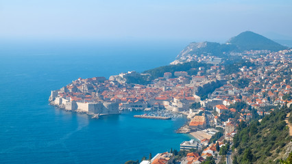 Fototapeta na wymiar Stunning top view on Dubrovnik in Dalmatia, Croatia. Small bay with fortress towers on the sides. Fort Lovrijenac and stone pier with a lot of boats in the cove. Travel Croatia