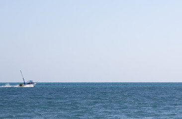 Motor boat heading towards the sea. Nothing more but empty horizon. Boat composed to the left where the focus point is. Copy space.