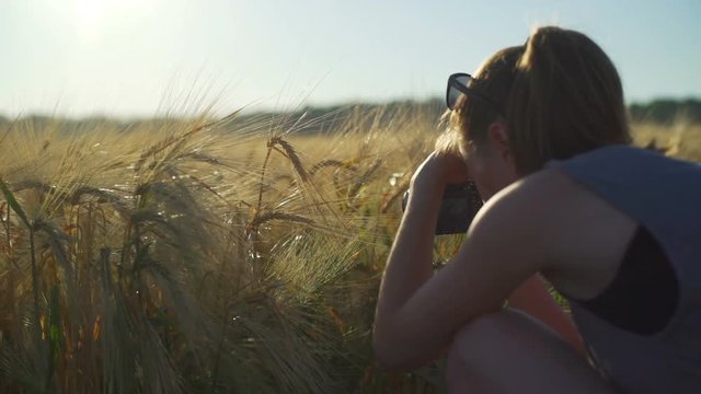 Young woman taking photos with camera on the wheat field sunny rapid slow motion