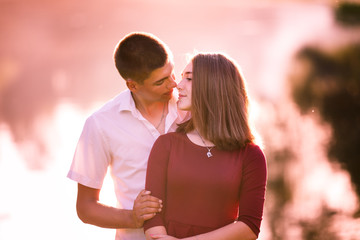 Portrait of a beautiful young couple in love standing and kissing near the river.
