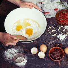 Baking background with ingredients for fruit and chocolate cake; with woman hands 