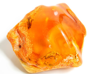 A large and colorful piece of amber on a white background. A natural mineral. The sun stone is orange. Bright polished amber of unusual shape with inclusions and insects