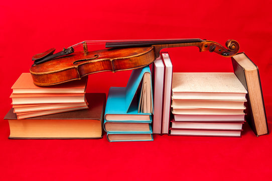 Music instrument old violin on a book and pile of books