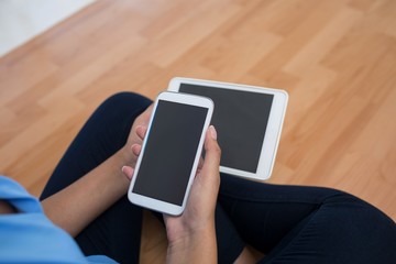Female executive holding mobile phone and digital tablet