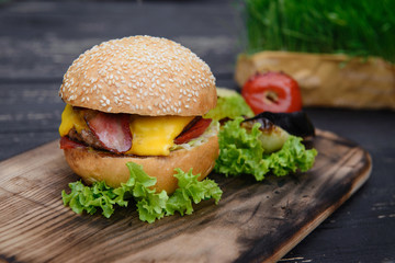 Cheeseburger on the wooden table with grilled vegetables