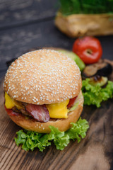 Cheeseburger on the wooden table with grilled vegetables