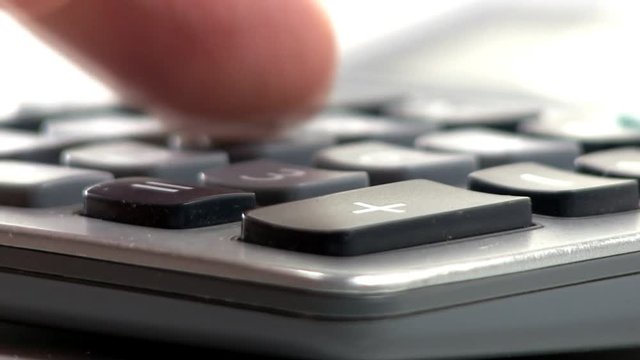 A man enters numbers into calculator with macro view of keypad at low angle