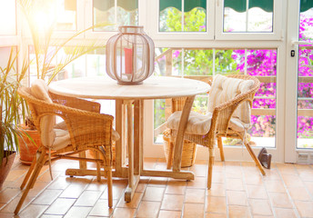 Interior of sunny empty summer cafe terrace with table and wicker chairs