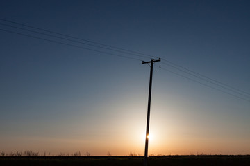 Silhouetted Power Pole On Canadian Prairie At Sunrise