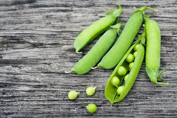 Pods of green peas on a old wooden surface close up, top view