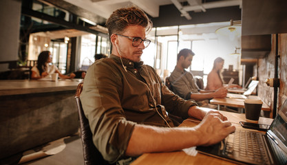 Young man sitting at cafe and using laptop