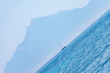 Tilted view of a sailboat on the horizon, with mount Athos looming in the background in Chalkidiki, Greece